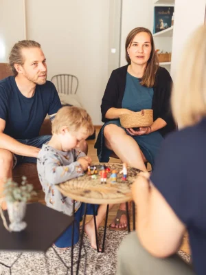 Thea Josi Stauber, psychologische Beraterin von Vertrauenswelt, über die Schulter hinweg, fotografiert mit Sicht auf eine junge Familie, welche die Familienberatung von Vertrauenswelt in Anspruch nimmt.