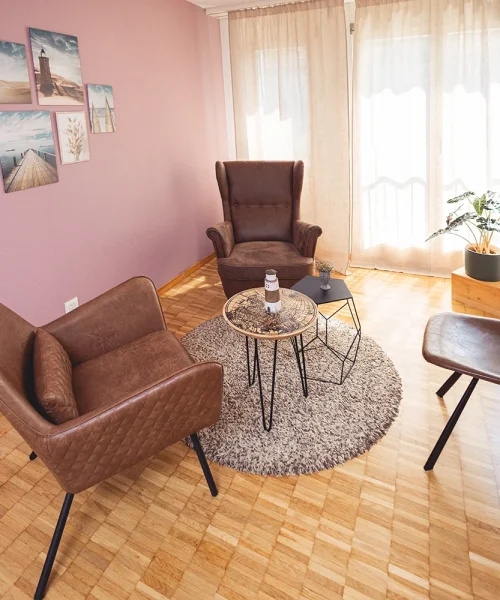 Der Beratungsraum von Vertrauenswelt in Riedikon bei Thea Josi zu Hause. Ein heller gemütlicher Raum mit Holzboden und grünen bequemen Sesseln.