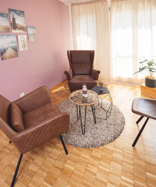 Der Beratungsraum von Vertrauenswelt in Riedikon bei Thea Josi zu Hause. Ein heller gemütlicher Raum mit Holzboden und grünen bequemen Sesseln.